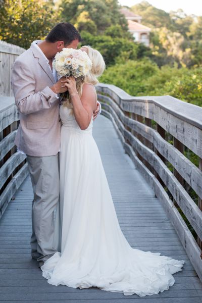 Bride and groom kissing behind a bouquet