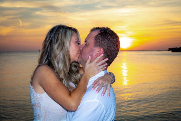 Wedding Couple kiss on the beach in front of the setting sun after their wedding planned by Southernmost Weddings