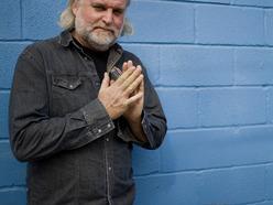 guy with white beard standing against blue wall